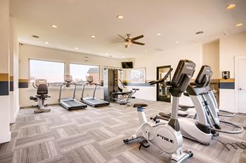 A gym with a variety of exercise equipment including treadmills, stationary bikes, and elliptical machines.